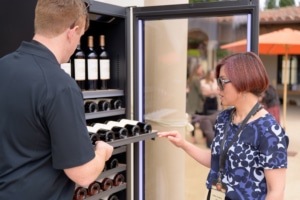 Man showing wine in a wine fridge to a woman in the Vintec Lounge