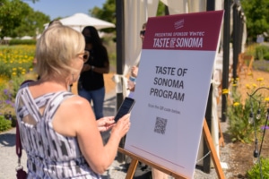 Woman scanning a QR code on a Taste of Sonoma event sign