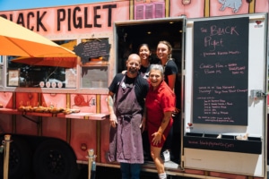 Black Piglet food tuck staff standing in front of the truck door opening