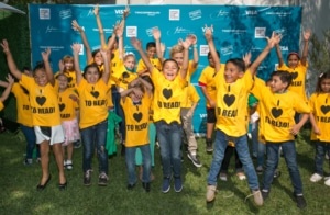 Children jumping and smiling while wearing I Love to Read T-shirts